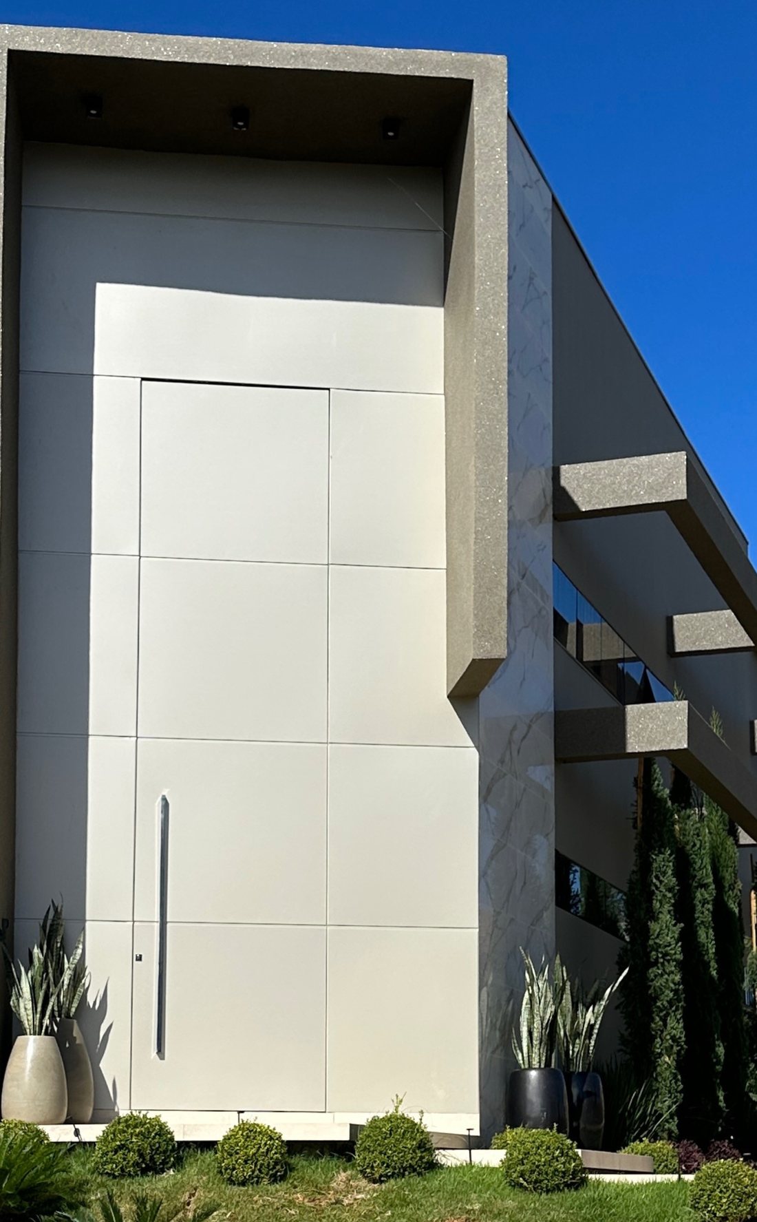 Porta pivotante branca em ACM de uma residência