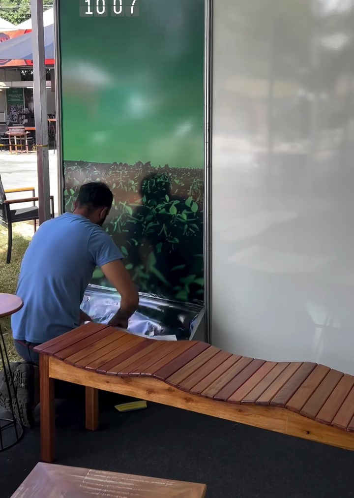 Instalador da Impresilk aplicando adesivo na parede de um estande